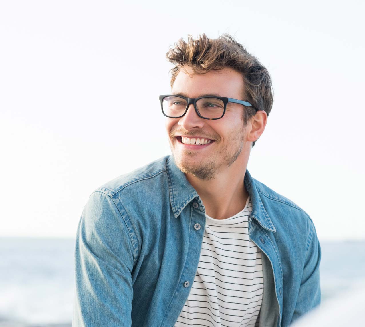 Male wearing glasses smiling at the beach