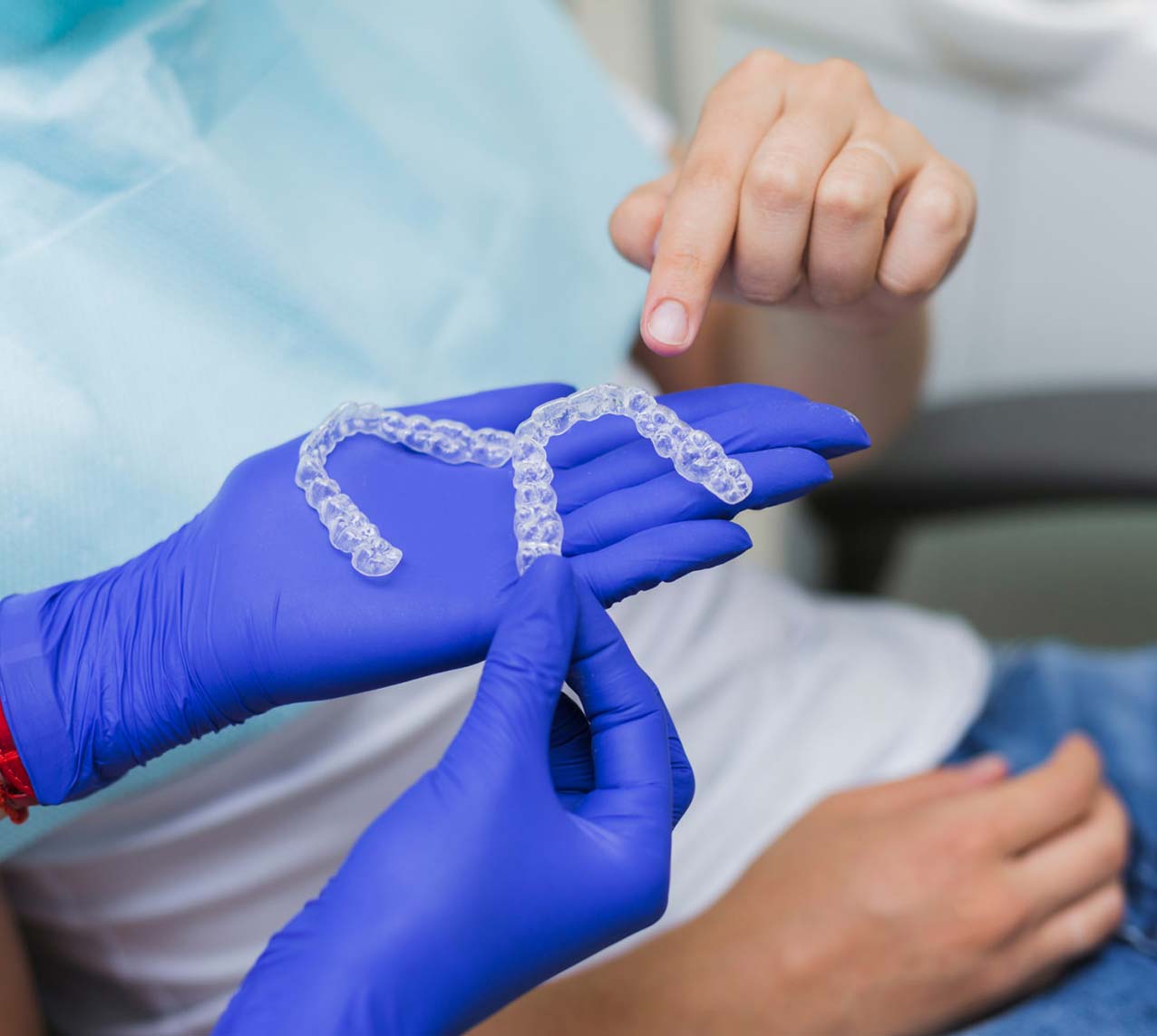 Invisalign clear retainer trays in dentists hands