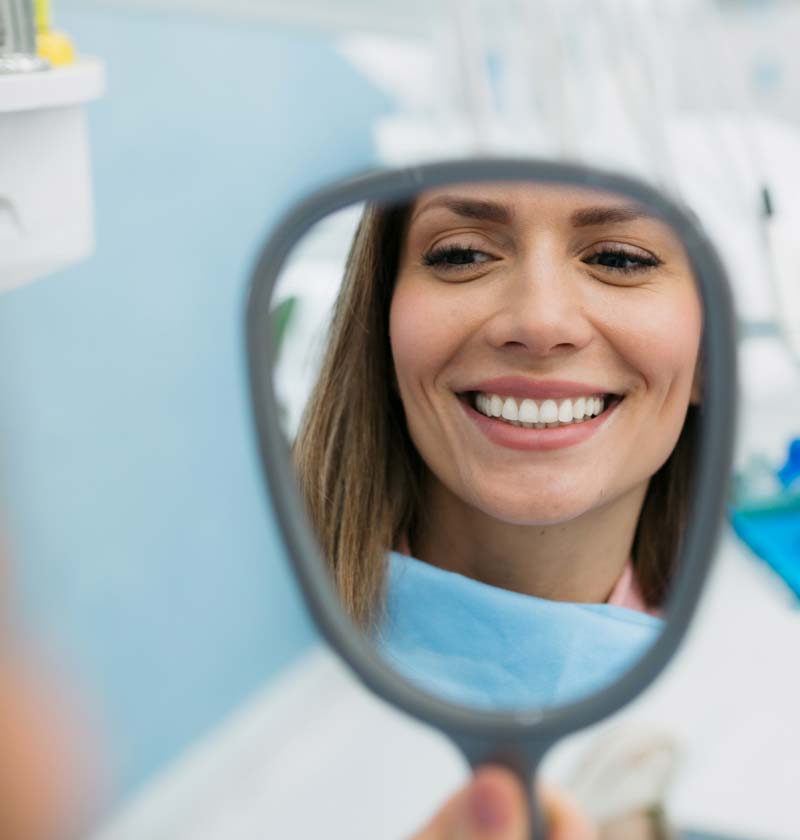 Woman looking at teeth in the mirror